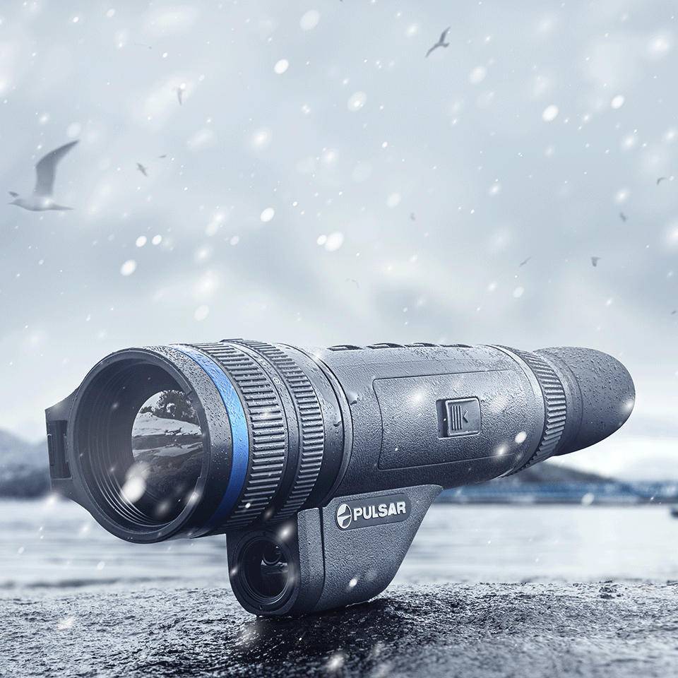 Pulsar Telos XP50 thermal monocular in snowy outdoor setting, highlighting waterproof design and rugged build for extreme conditions.