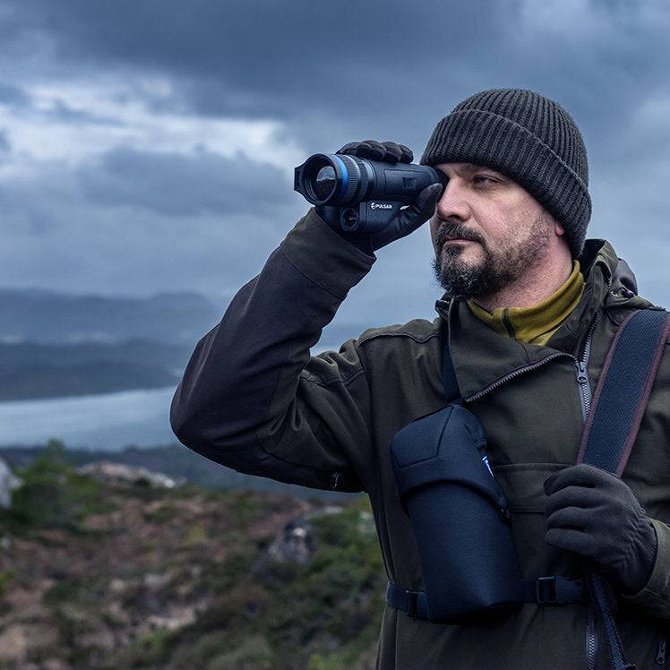 Man using Pulsar Telos XQ35 LRF thermal monocular in mountainous terrain, demonstrating its long-range detection and ergonomic design.